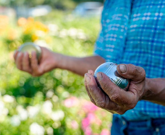 Persona mayor participando en una partida de petanca, fomentando la socialización y la actividad física en la comunidad